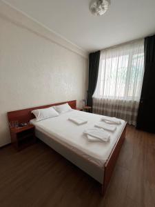 a bedroom with a bed with white sheets and a window at Гостиница Берлога in Pavlodar