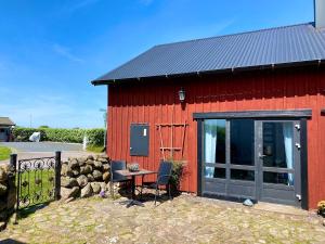 a red barn with a table and chairs in front of it at Charming 5 bed studio at Getterön in Varberg