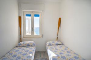 two beds in a room with a window at I Gradini sul Mare in Santa Maria