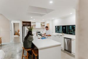 a man and a woman sitting at a kitchen counter at Wildwood Retreat a Luxury Vineyard Escape in Yallingup Siding