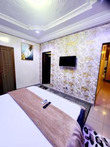 une chambre avec un grand lit et un mur en pierre dans l'établissement Mini Meublé au rez de chaussée, à Dakar