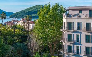 a white building with trees and a body of water at Hotel Majestic in Budva