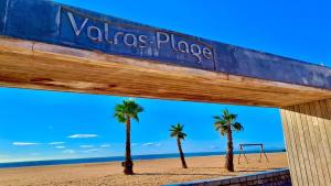 two palm trees and a sign on a beach at Maison Sympa in Valras-Plage
