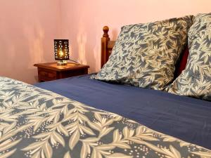 a bed with a blue comforter and a lamp on a table at Maison Sympa in Valras-Plage
