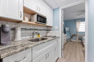 a kitchen with white cabinets and a sink at 301 Ocean Ave, Unit 110 - The Harbor Light in North Wildwood