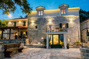 una casa de piedra con un banco delante en Villa Eterna 1806, en Blato na Cetini
