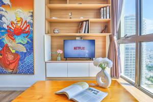 a living room with a tv and a table with a book at SeaSky View Suites - Gold Coast Tower, Nha Trang Beach & Lotte Mall in Nha Trang