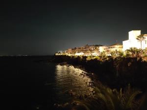 a building on a cliff near the water at night at U Casteddu - Case Vacanza Aci Castello in Aci Castello +5 photos