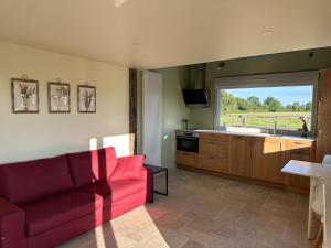 a living room with a red couch and a kitchen at La Maison Poulette in Ticheville