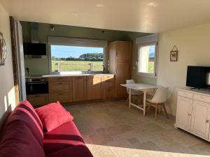 a living room with a couch and a kitchen with a table at La Maison Poulette in Ticheville