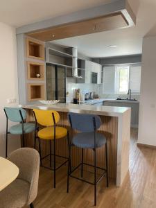 a kitchen with three bar stools and a counter at Casa Bambu, Paraiso na Terra in Praia Verde