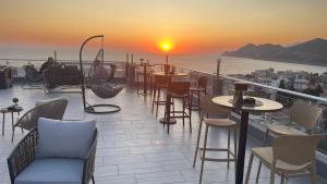 a rooftop patio with tables and chairs and a sunset at Elma Apartments Dobra Voda in Dobra Voda +25 photos