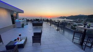a rooftop patio with tables and chairs and the sunset at Elma Apartments Dobra Voda in Dobra Voda
