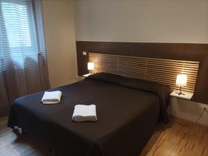 una camera da letto con un letto nero con due asciugamani di Ai Gabbiani a Verona