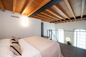 a bedroom with a white bed in a room with wooden ceilings at Maison Selva - Palazzo Cervi Duplex Superior in Salò