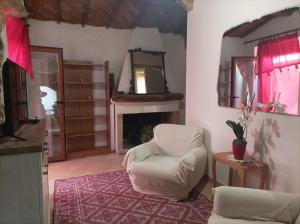 ein Wohnzimmer mit einem weißen Stuhl und einem Kamin in der Unterkunft Domus Maria in Milis