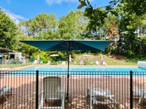 ein schwarzer Zaun mit Stühlen und einem Sonnenschirm vor einem Pool in der Unterkunft Jolie maison au cœur de la Marina Talaris Lacanau in Lacanau