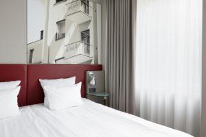 a bedroom with a white bed with a red headboard at Original Sokos Hotel Albert in Helsinki
