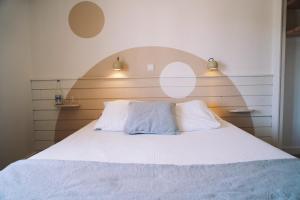 a bedroom with a white bed with two pillows at Hôtel Dune Saint-Pierre in Saint-Pierre-Quiberon