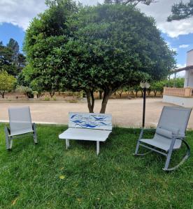 two chairs and a bench in the grass with a tree at Meraviglia d'Otranto in Otranto