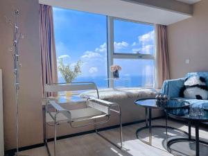 um quarto de hospital com uma mesa e uma grande janela em Azure Haven Seaview Suites Shilaoren Coast em Qingdao mais 133 fotografias