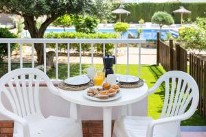 a white table with a plate of donuts and orange juice at RVApartaments Escala Brava in L'Escala