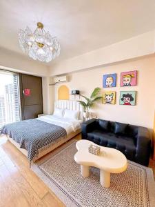 um quarto com uma cama, um sofá e um lustre em Azure Haven Seaview Suites Shilaoren Coast em Qingdao