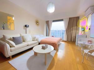 uma sala de estar com uma cama e um sofá em Azure Haven Seaview Suites Shilaoren Coast em Qingdao