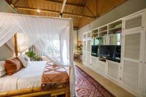una camera con letto a baldacchino e TV di Bloomfield Umalas a Canggu