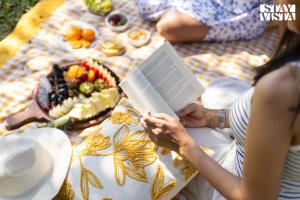 due persone sedute su una coperta che leggono un libro di StayVista at Vaana - Glamping Tents, Jacuzzi, Pool a Lonavala
