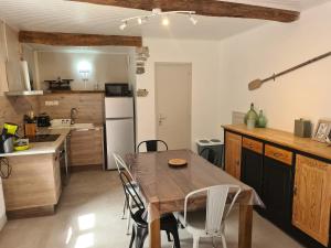 a kitchen with a wooden table and white chairs at Gite cap de biou in Penne