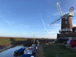 滨海克雷Lovely quiet cottage Sleeps 4 adults, 4 children, Dog Friendly的河边有船的风车