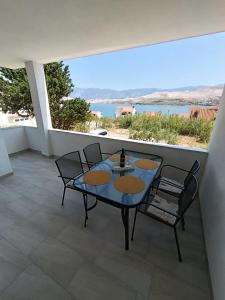 a patio with a table and chairs and a view of the water at Apartments Višnja in Pag