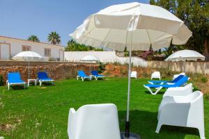 a group of chairs and an umbrella in the grass at Quinta da Ponte in Odiáxere