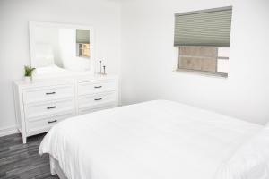 Habitación blanca con tocador blanco y espejo en Location! Quality! Comfort! The downtown Gem, en Naples