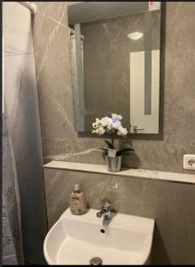 a bathroom sink with a mirror and a vase of flowers at Gemütliche Wohnung im Herzen von Heidelberg in Heidelberg