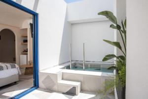 a bathtub in the middle of a room with a mirror at Dimitra Boutique Rooms in Faliraki