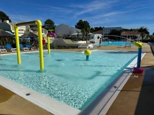 a swimming pool with blue water and yellow poles at Les sables chal’heureux in Saint-Jean-de-Monts