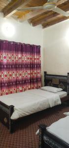 a bedroom with two beds and a curtain at Hunza Backpacker Inn in Karimabad Hunza +14 photos