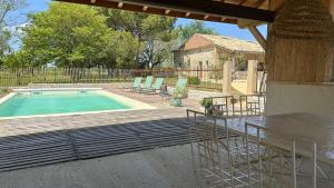 a swimming pool with a table and chairs next to a building at Une pause nature chez Marion et Cédric in Montignac-Toupinerie