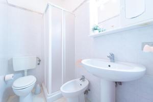 a white bathroom with a toilet and a sink at La Casa della Riviera in Platamona +23 photos