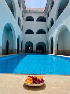 a bowl of fruit on a plate next to a swimming pool at Villa al Andalous in Sidi Krir 