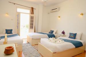 a bedroom with three beds with blue and white at Ekadolli Nubian house- by kerma hospitality in Aswan