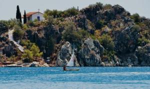 a person on a surfboard in the water near an island at Thalassa loft in Tolo in Tolo