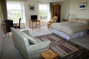 a bedroom with a bed and a couch and a chair at Lammas Park House in Dawlish