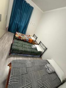 a bedroom with two beds and a blue curtain at Cataleia in Biella +4 photos