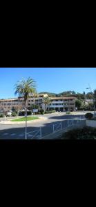 a view of a parking lot with a palm tree and buildings at appartement à 5 min à pieds de la plage in Les Lecques