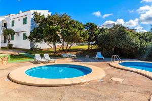 a swimming pool with two chairs and a house at Apartamento Biniforcat in Cala en Forcat