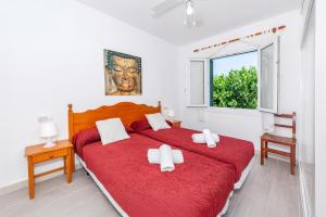 a bedroom with two beds with red sheets and a window at Apartamento Biniforcat in Cala en Forcat