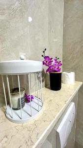 baño con lavabo y flores púrpuras en una encimera en Sea View Aroma Apartments, en Bar